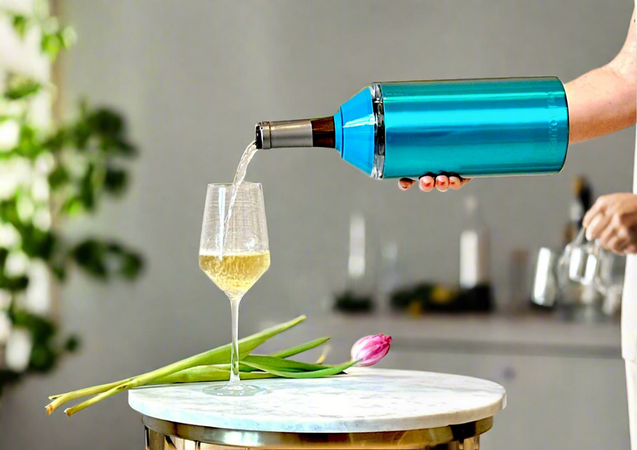 Turquoise Carrovino Wine & Champagne Chiller pouring chilled wine into a glass on a table with tulip and green leaves.